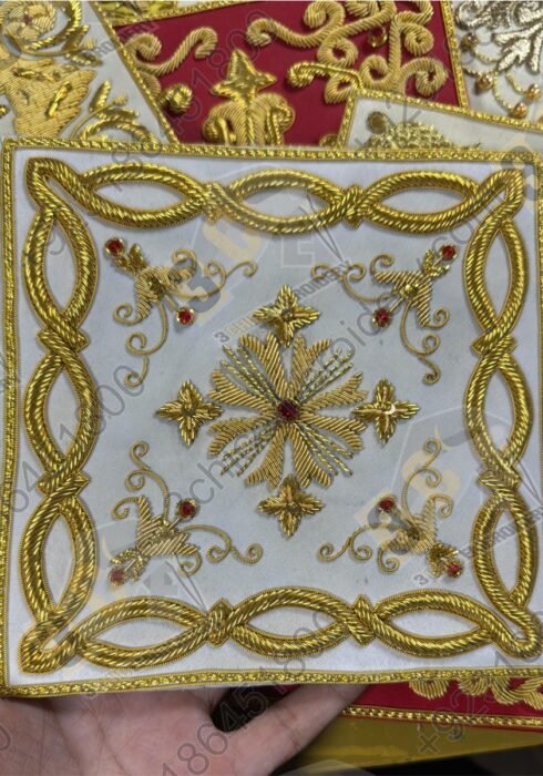 Hand embroidered goldwork badge with decorative border and cross motif